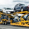 Car Shipping Services truck transporting multiple vehicles on a multi-level carrier trailer along a highway.