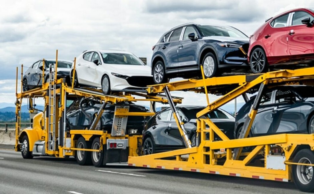Car Shipping Services truck transporting multiple vehicles on a multi-level carrier trailer along a highway.
